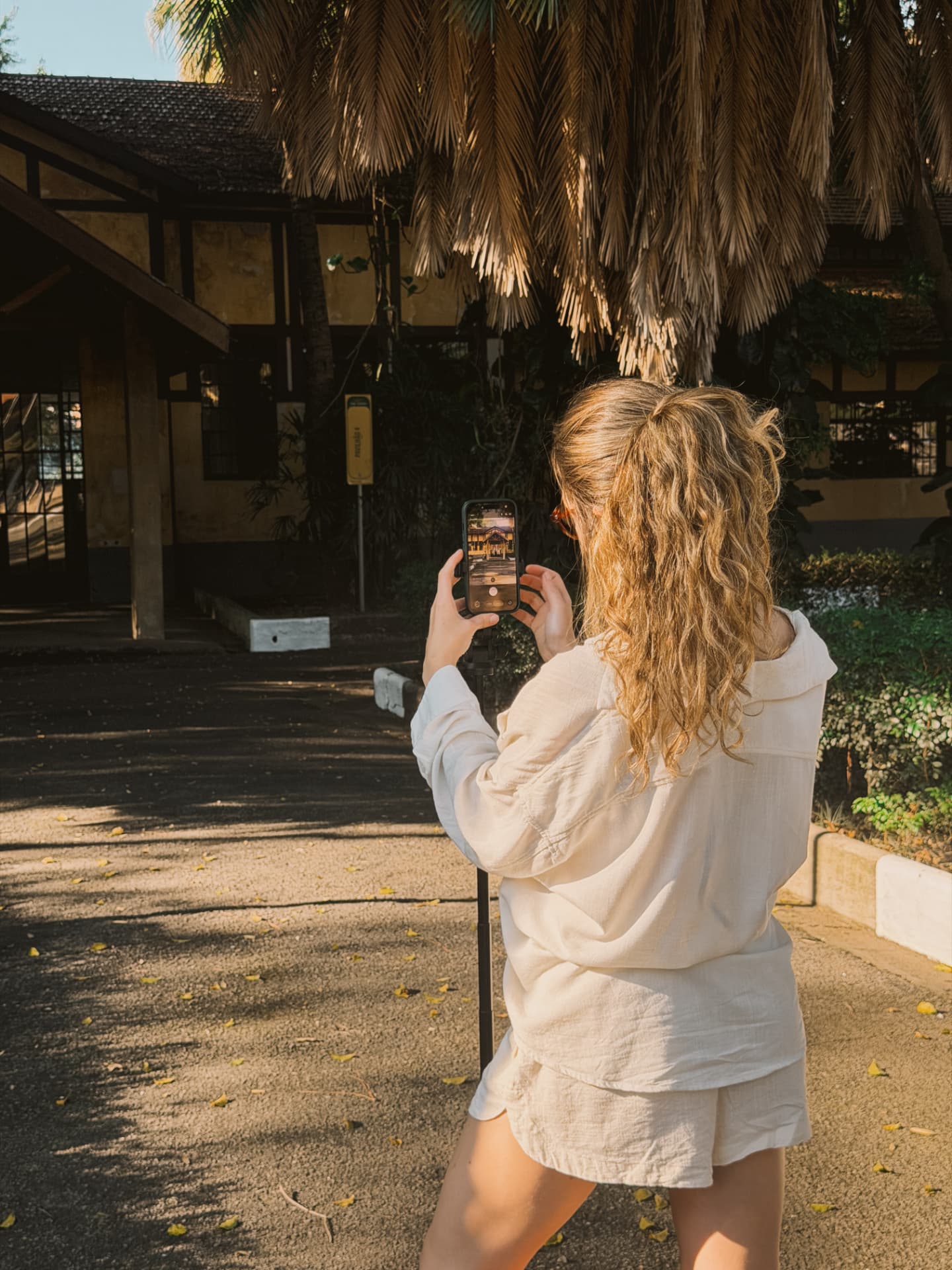 Nicole fotografando com o iPhone sob uma sombra de palha